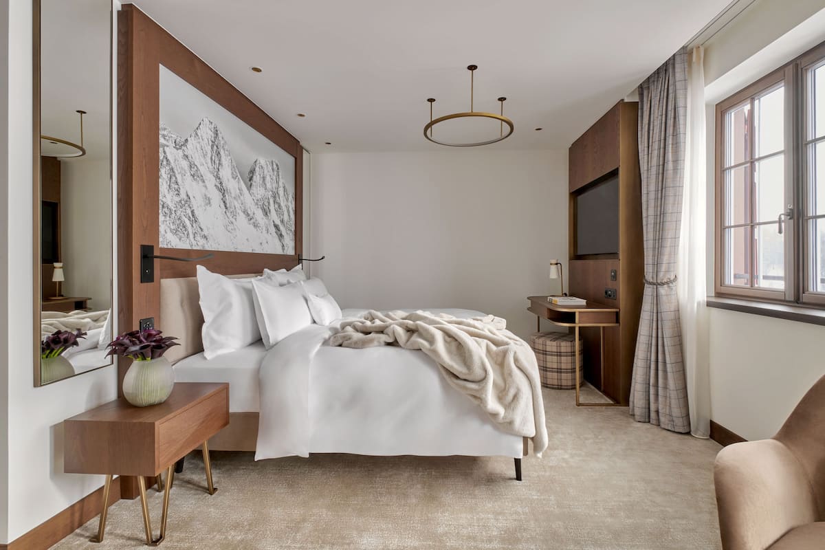 A modern bedroom with a bed, bedside table, and a large window.