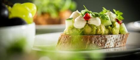 A sandwich with avocado, cheese, and greens on a slice of bread.