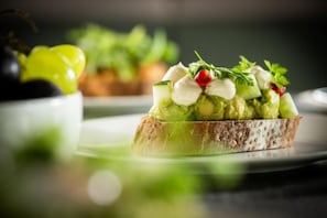 A sandwich with avocado, cheese, and greens on a slice of bread.
