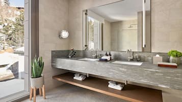 Un baño moderno con un espejo grande, dos lavamanos y una planta en maceta.