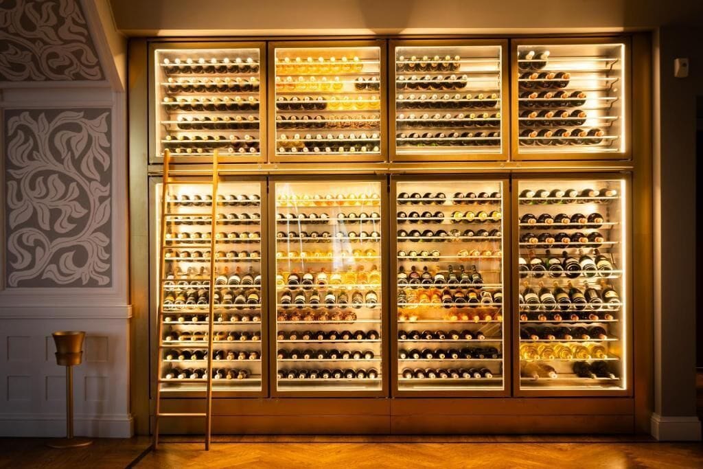 Una bodega con varios estantes de vidrio llenos de botellas de vino.