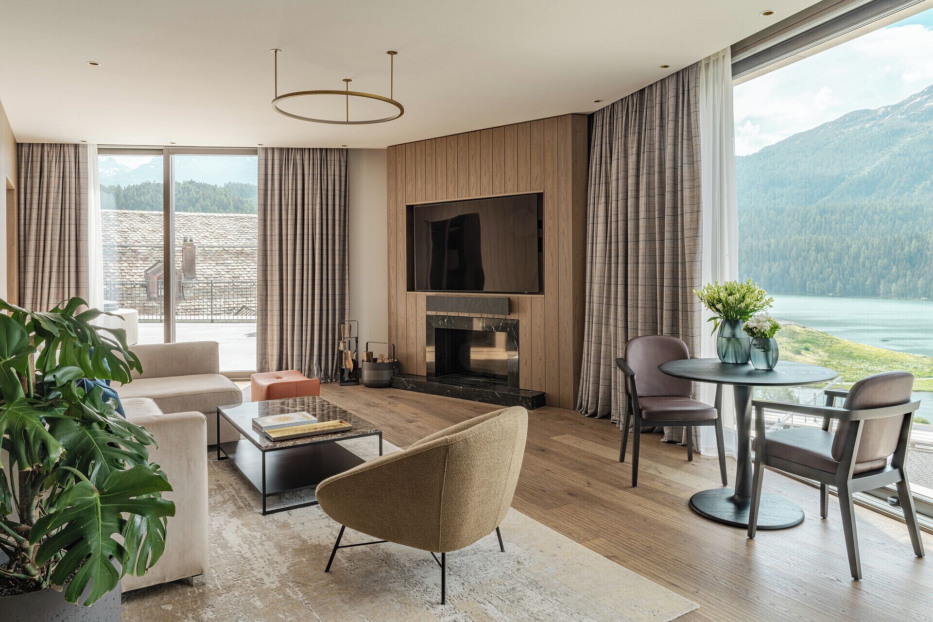 A modern living room with a fireplace, large windows, and a view of a lake and mountains.