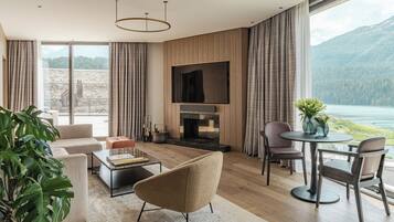 A modern living room with a fireplace, large windows, and a view of a lake and mountains.