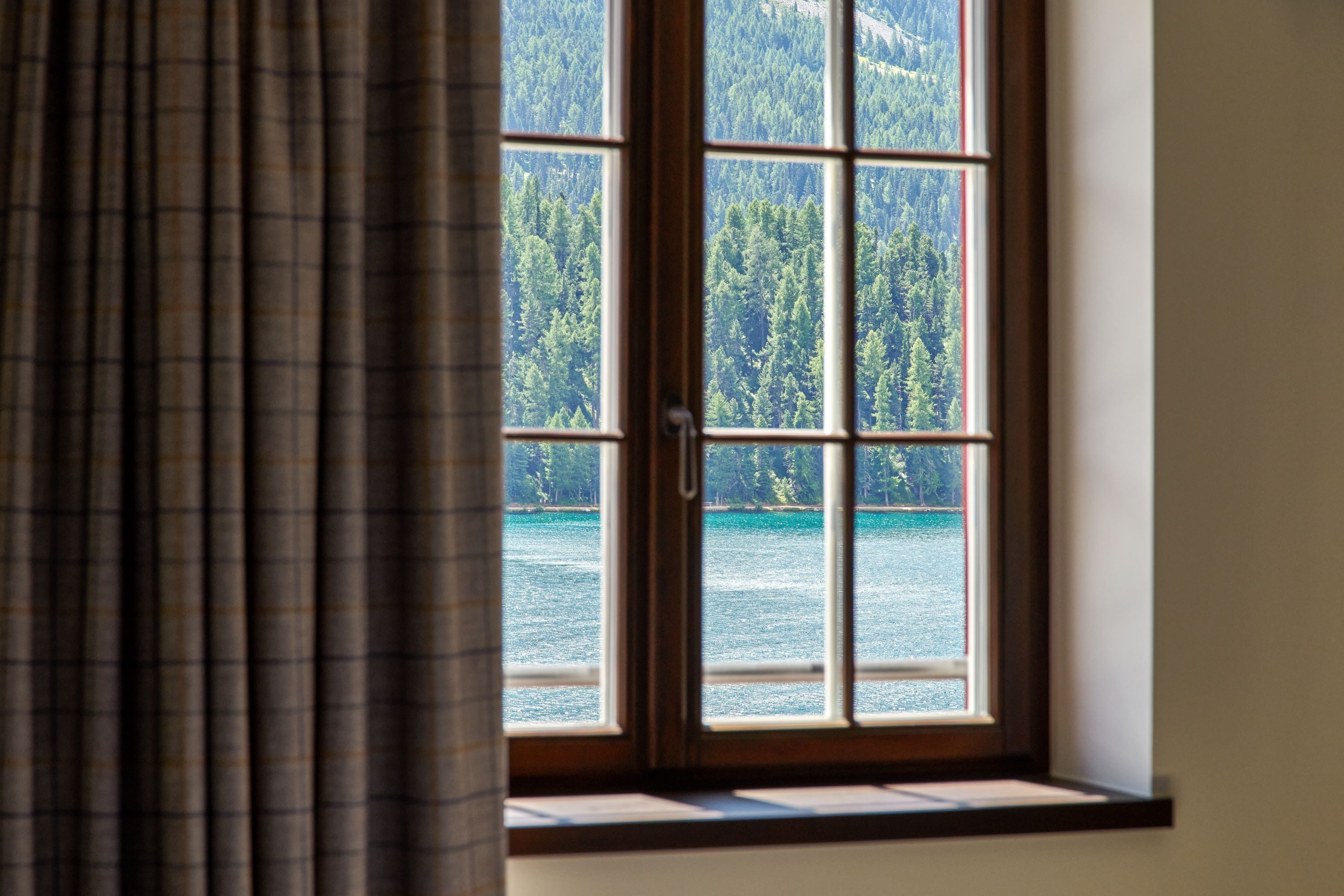 Una ventana con vistas a un área boscosa y una masa de agua.