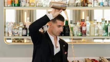 Un bartender vertiendo una bebida en una coctelera.