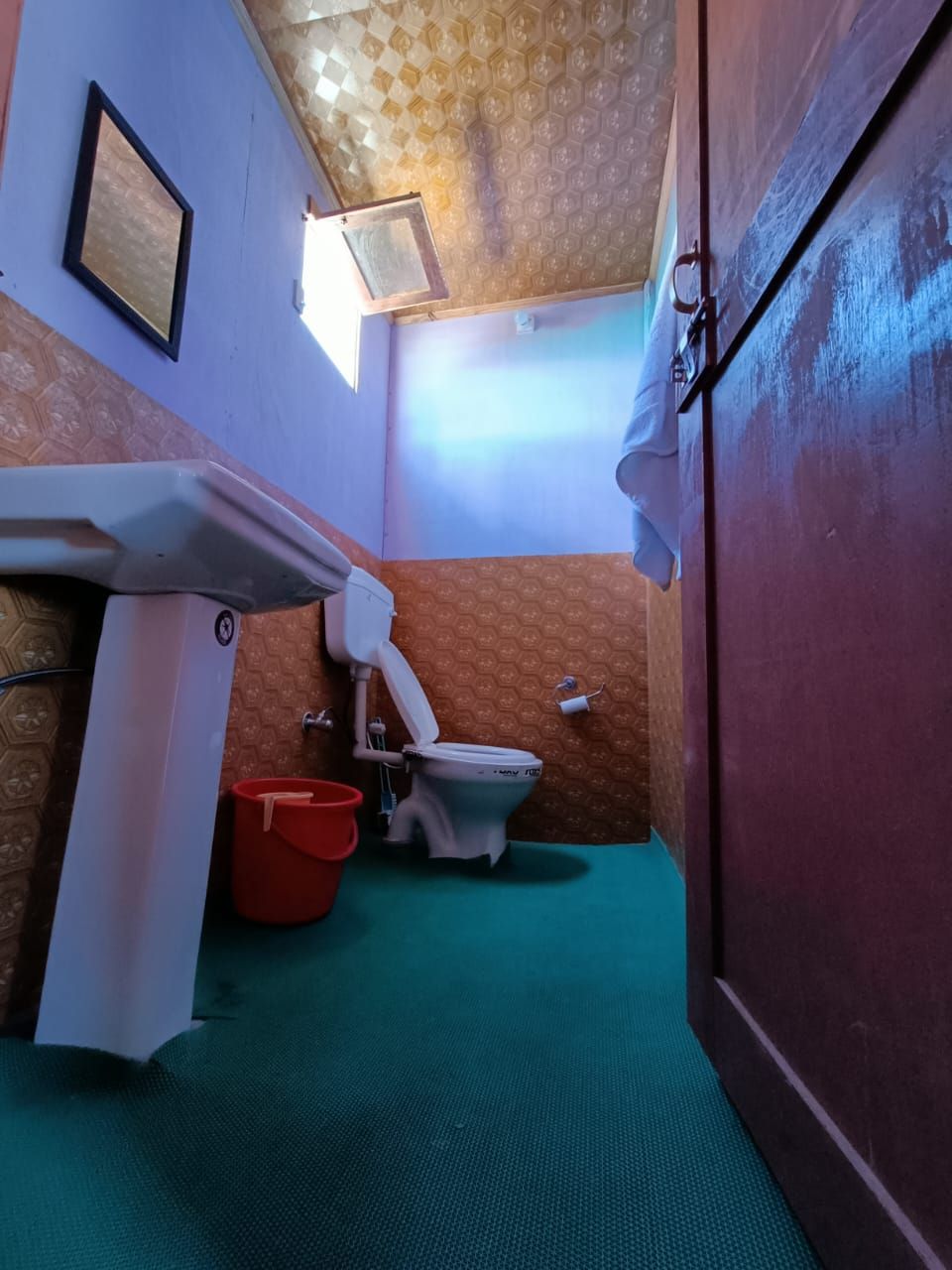 A small bathroom with a toilet, a sink, and a red bucket.