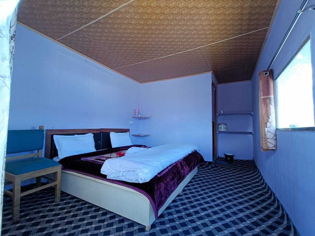 Un dormitorio pequeño y acogedor con una cama individual, una silla y una estantería con una taza.