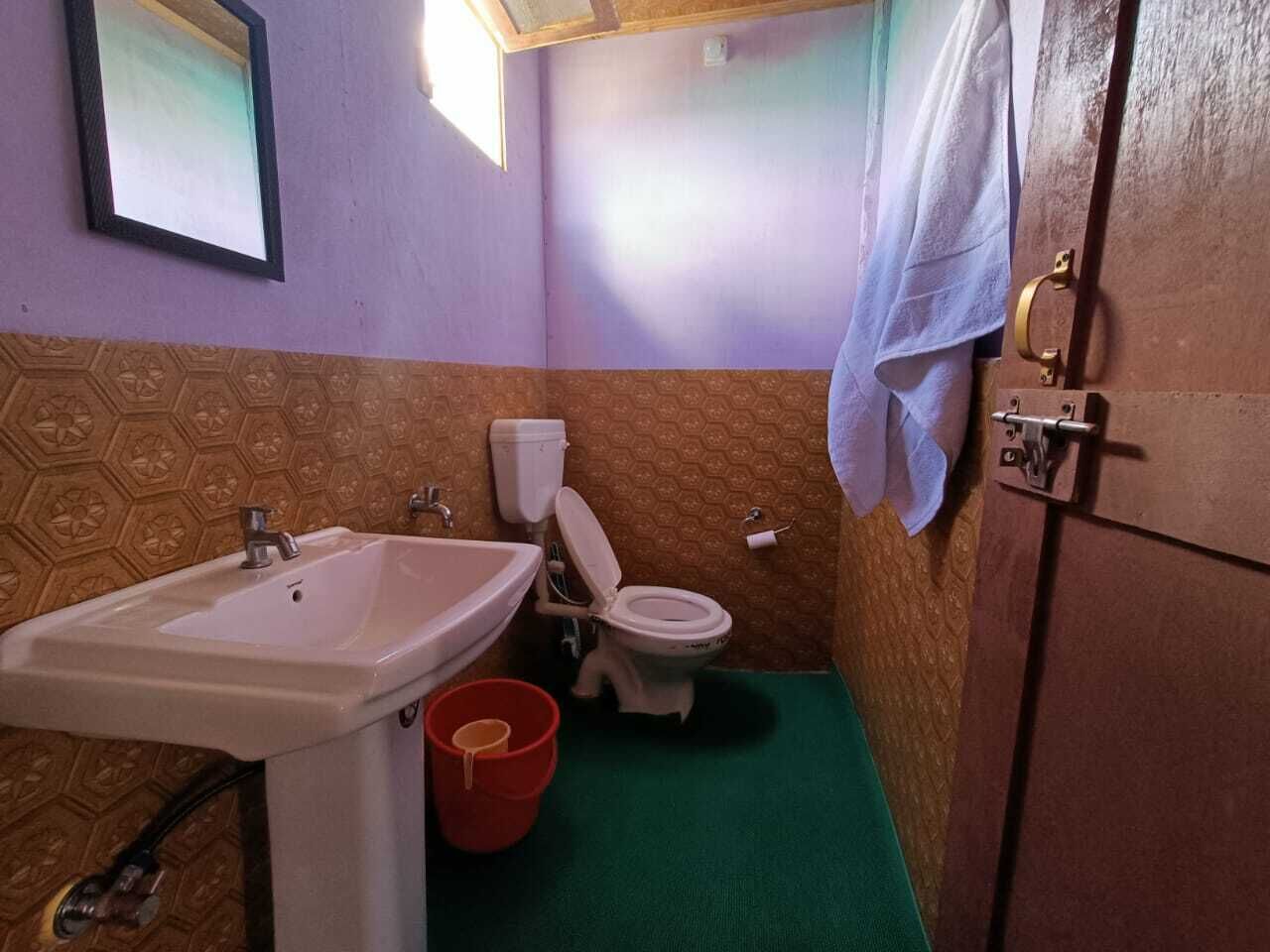 Une salle de bain avec un lavabo, des toilettes et un seau rouge.