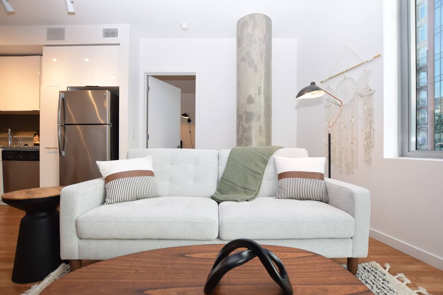 A modern living room with a sofa, a coffee table, and a large pillar.