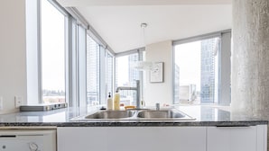 A modern kitchen with a double sink, large windows, and a view of the cityscape. - Sophari Towers: Bellevue Apartments  (Bellevue)
