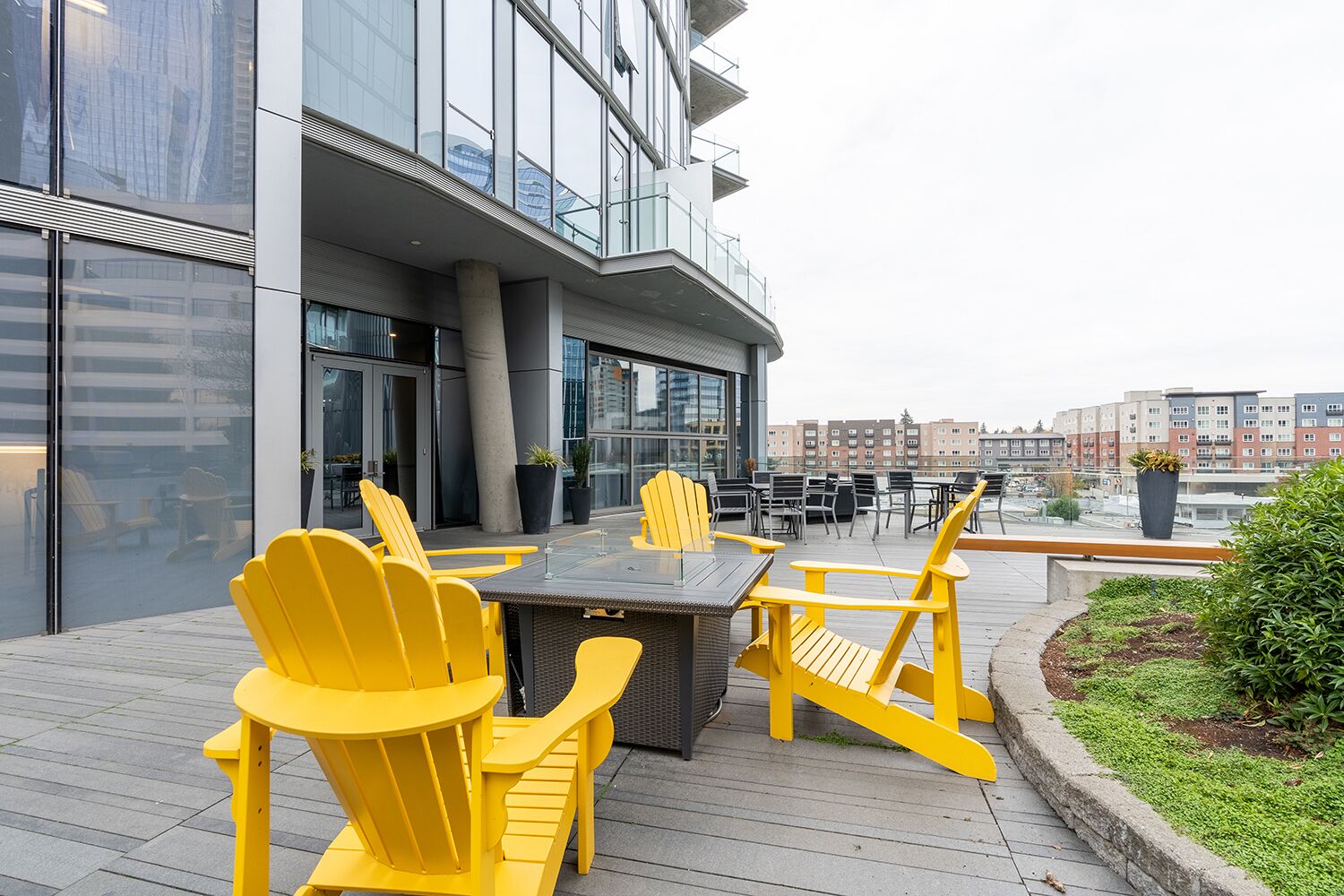 An outdoor seating area with yellow chairs and a table, overlooking a cityscape.