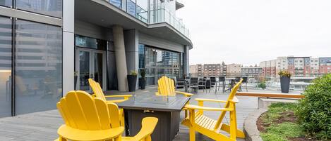 An outdoor seating area with yellow chairs and a table, overlooking a cityscape.