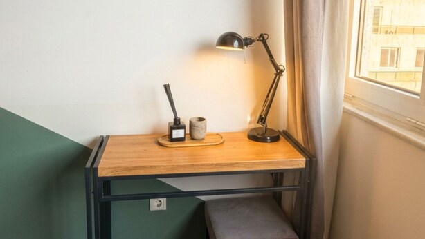 Un bureau d’angle avec une lampe, une tasse et un petit banc.