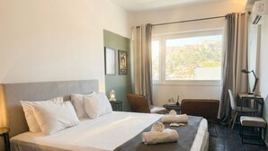 Une chambre d’hôtel avec un lit, un bureau, une chaise et une fenêtre avec des rideaux.