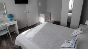 A bedroom with a bed, a desk, a TV, and a wardrobe.