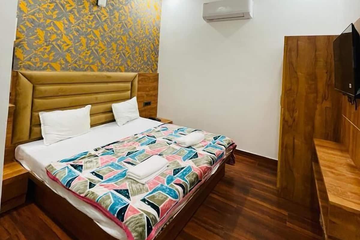 Un dormitorio con cama, ventilador de techo, equipo de aire acondicionado y banca de madera.