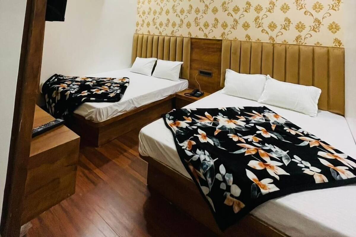 Habitación de hotel con dos camas, ventilador de techo, aire acondicionado y papel tapiz estampado.