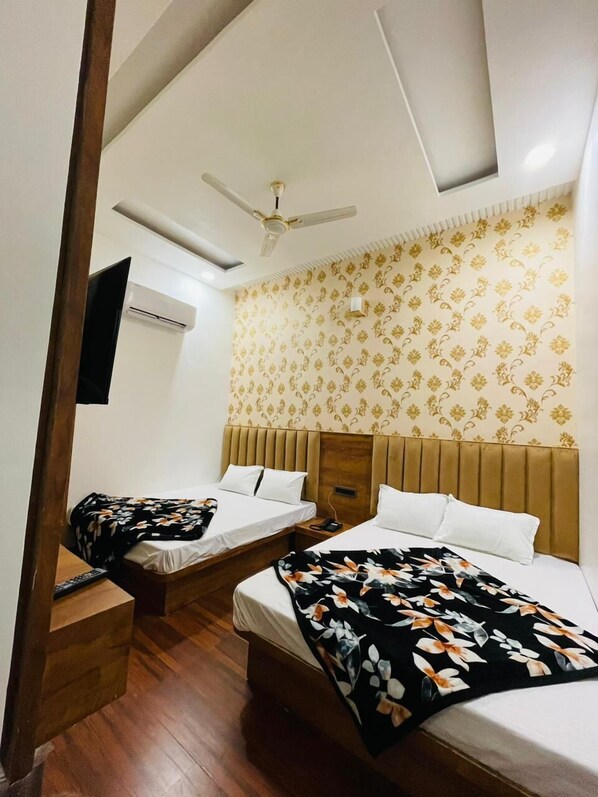 A hotel room with two beds, a ceiling fan, an air conditioning unit, and a patterned wallpaper.
