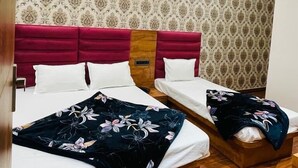 A hotel room with two beds, a red headboard, patterned wallpaper, and a ceiling fan. - Hotel 4S Niwas (Amritsar)
