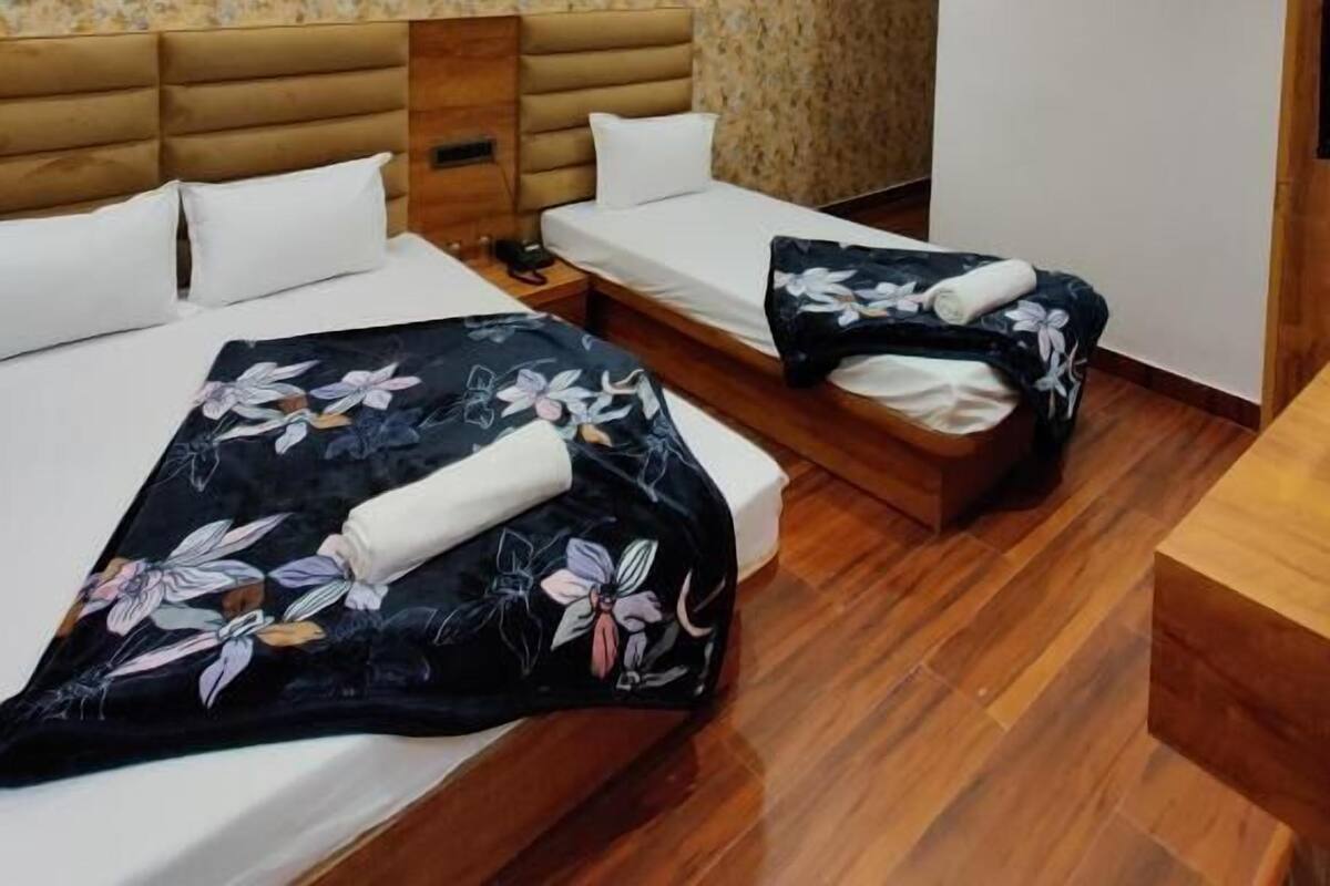 Habitación de hotel con dos camas, ventilador de techo, aire acondicionado de pared y cabecero de madera.