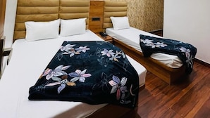 A hotel room with two beds, a ceiling fan, and an air conditioning unit. - Hotel 4S Niwas (Amritsar)