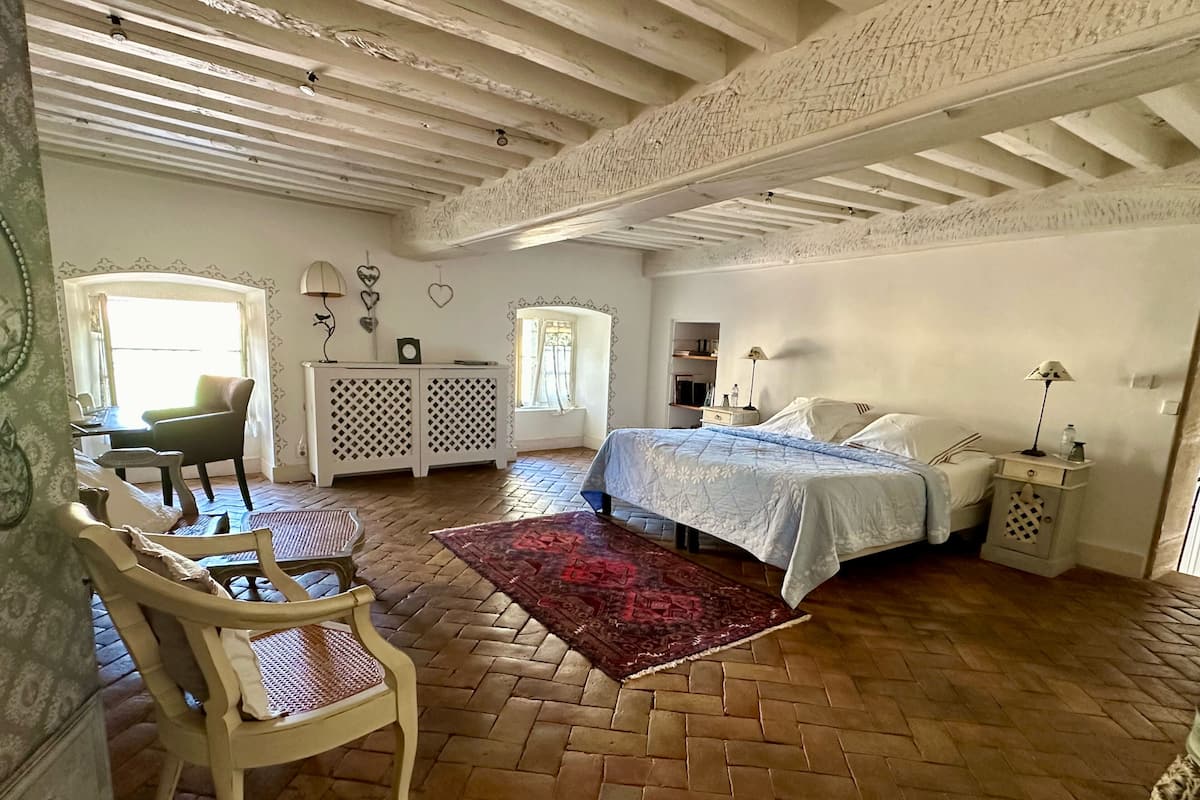 A bedroom with a bed, a desk, a chair, a window, and a wardrobe.