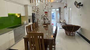 Une cuisine moderne avec un coin repas, comprenant une table à plateau en verre, des chaises en bois et un élément de séparation décoratif.