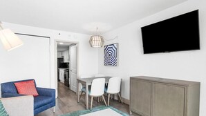 A modern living room with a sofa, a dining table with chairs, a TV mounted on the wall, and a cabinet. - Unparalleled Oceanfront Luxury 6th Floor (Myrtle Beach)