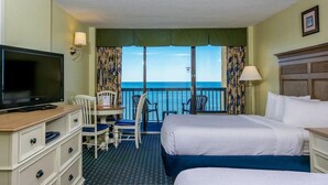 A hotel room with two beds, a TV, a desk with a chair, and a view of the ocean. - Coast Comfort Queen Efficiency 10th Floor (Myrtle Beach)