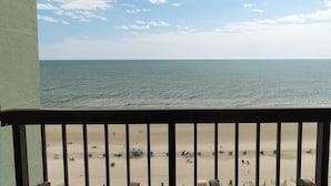 Blick auf einen Strand vom Balkon mit Geländer, feinem Sand und dem Meer.