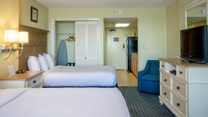 Une chambre d’hôtel avec deux lits, un bureau avec une lampe, une commode, une télévision et une chaise bleue.