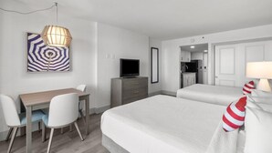 Een hotelkamer met een bed, een bureau, een stoel, een televisie en een lamp.