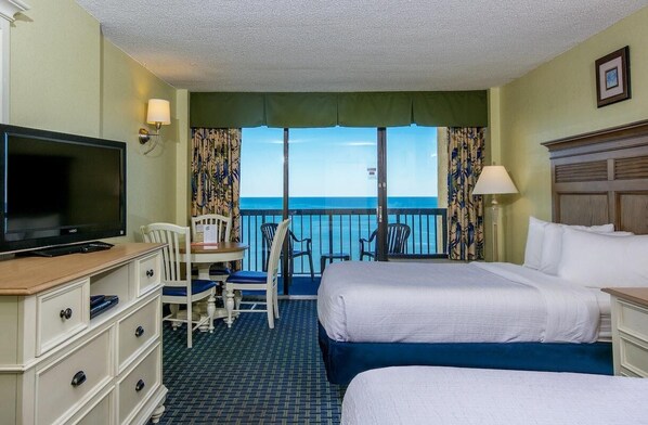 A hotel room with two beds, a TV, a desk with a chair, and a view of the ocean. - Sun and Sand Queen Efficiency 3rd Floor (Myrtle Beach)