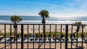 A balcony with a view of the beach, sun loungers, and a palm tree. - Seashells by the Seashore Cabana Room 2nd Fl (Myrtle Beach)