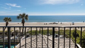 A beach view from a balcony with a pool and outdoor seating area. - Sun-Drenched Oceanfront Cabana Room 4th Flr (Myrtle Beach)