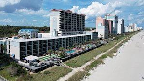 A hotel with a modern design, featuring a large pool area, a beachside location, and multiple buildings in the background. - Sun-Drenched Oceanfront Cabana Room 4th Flr (Myrtle Beach)