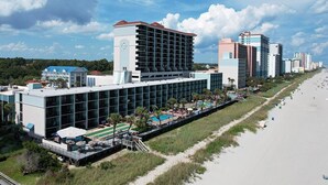 A hotel with a modern design, featuring a large pool area, a beachside location, and multiple buildings in the background. - Dreamy Getaway Oceanfront Cabana Room 4th Flr (Myrtle Beach)