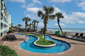 Relax by the oceanfront pool surrounded by palm trees and lounge chairs.