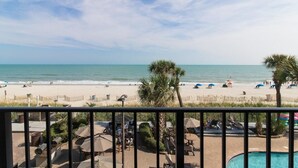 A beach view from a balcony with a pool, umbrellas, and lounge chairs. - Oceanfront Excellence Deluxe Rm 2nd Floor (Myrtle Beach)