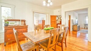 A dining area with a wooden table and chairs, a chandelier, and a view of the kitchen and living room through an open door. - Comfortable Downtown Napa Victorian - quiet & convenient
 (Napa)