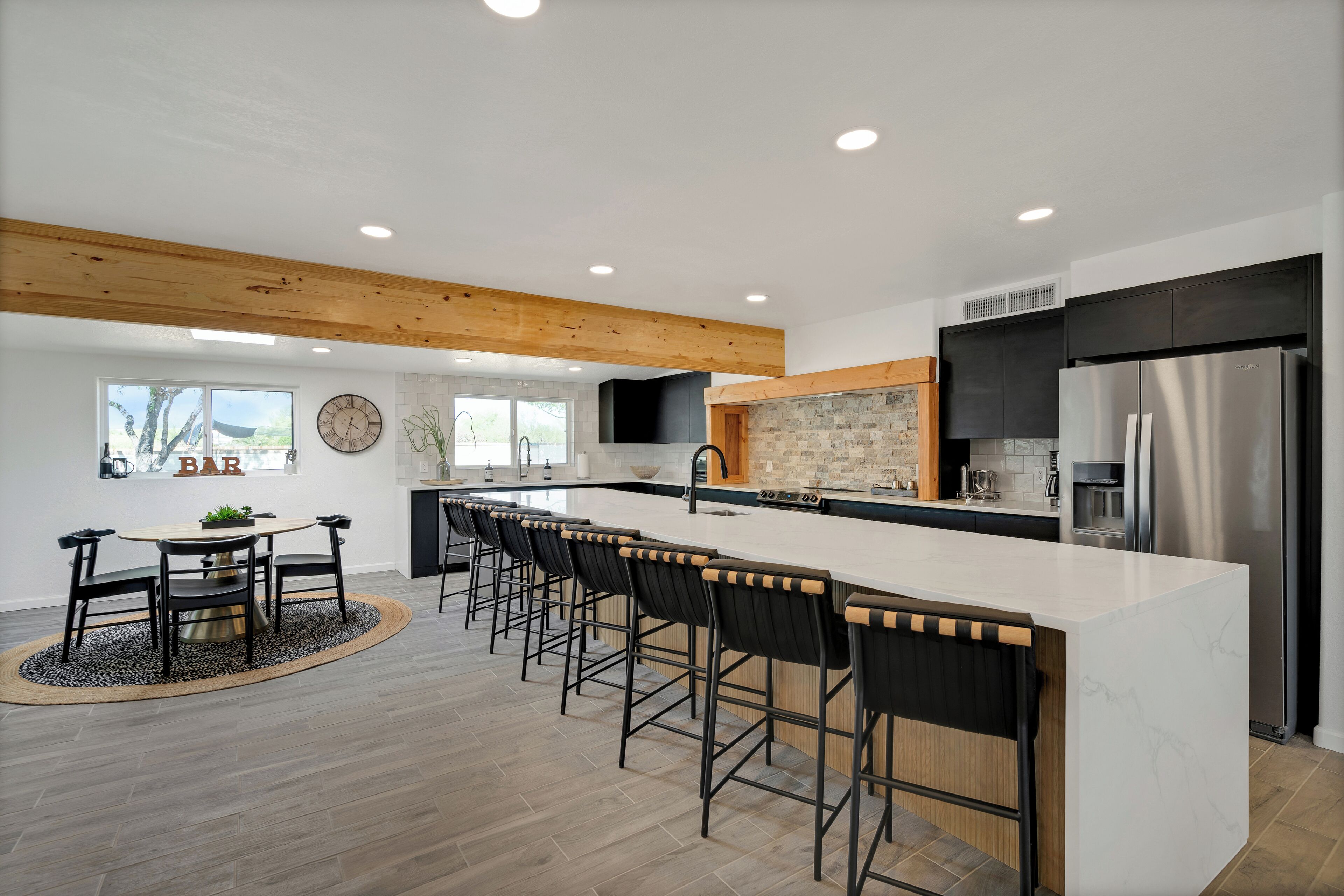 A modern kitchen with a large island, bar stools, and a dining area with a round table and chairs.