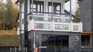 A two-story building with a balcony and a swimming pool in front. - Vuokatti Booking Suites   (Sotkamo)