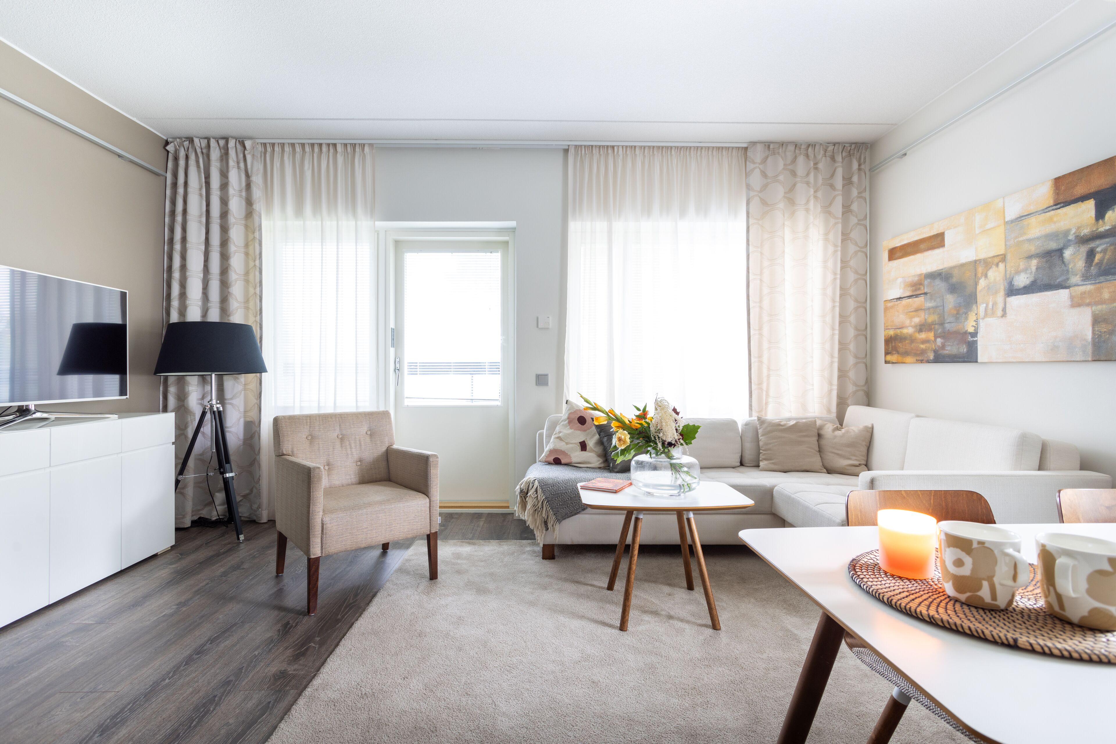 A modern living room with a sofa, armchair, coffee table, and a flat-screen TV.