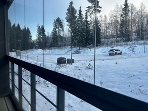 Un paysage enneigé avec une route, des arbres et un véhicule blanc.