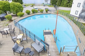 Une piscine avec une terrasse en bois, des chaises longues et un poste de surveillance pour les sauveteurs.