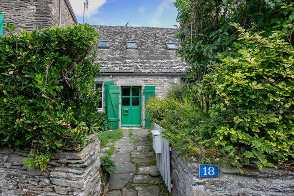 A stone house with a green door, a stone pathway leading to it, and a number sign '18' on the wall. - Holiday Home 'Ker Ar Vro - Maison Atypique' with Wi-Fi (Locquirec)