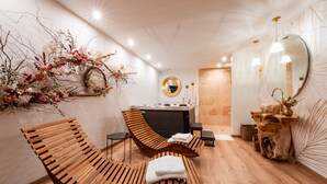 A modern spa room with wooden loungers, a large mirror, and a decorative wall arrangement.