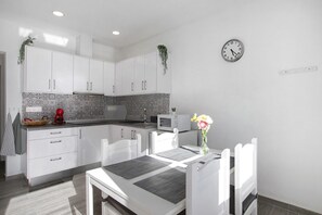 Une cuisine moderne avec des meubles blancs, un four à micro-ondes et une horloge au mur.