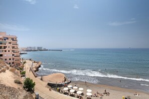 Un hôtel situé sur la côte, avec une plage, une promenade en bois et une scène.