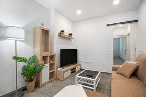 Un salon moderne comprenant un téléviseur, un canapé, une table basse, un lampadaire et une plante en pot.